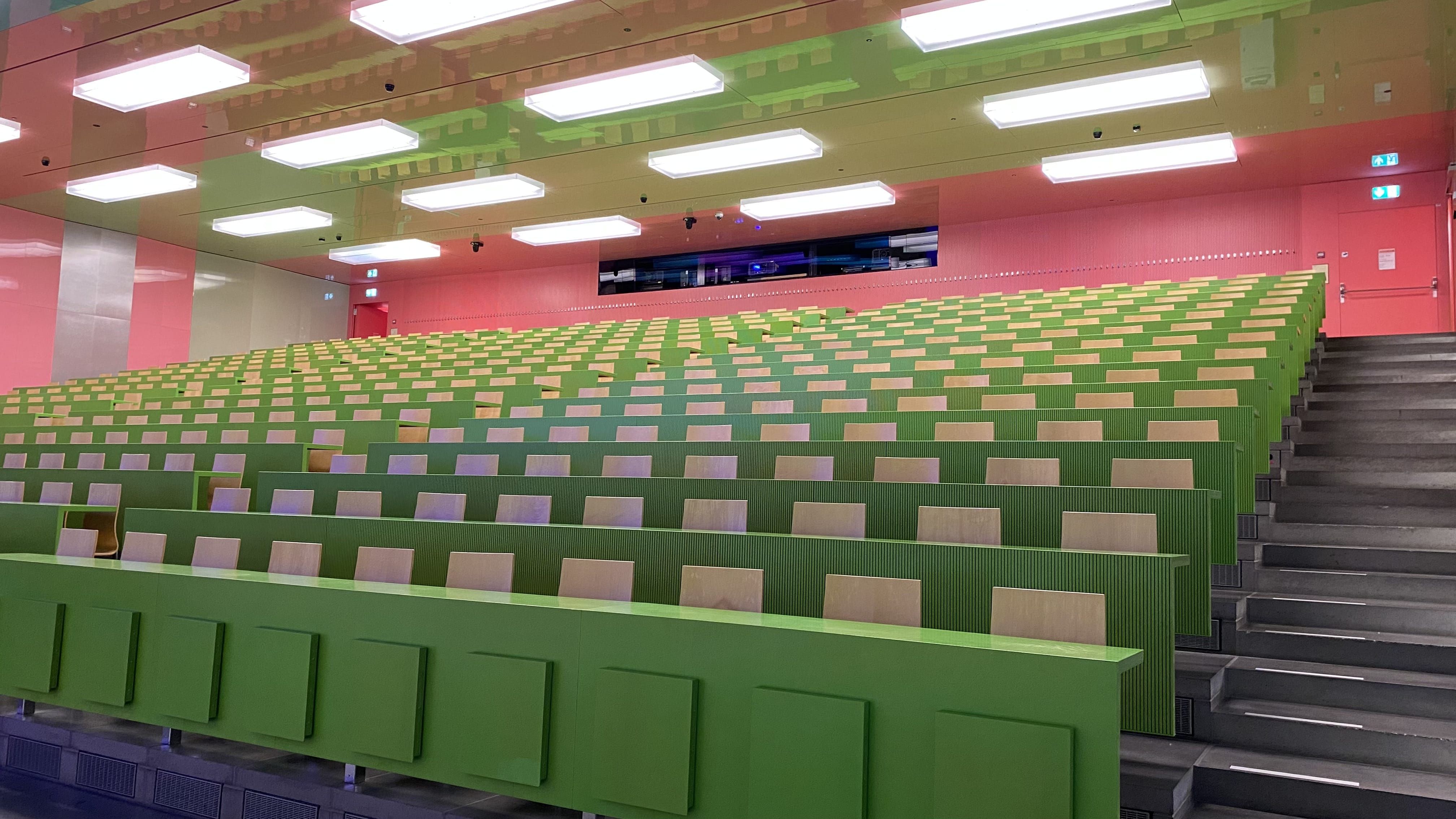 Hörsaal KOH-B-10: Ansicht auf den Raum vom Dozierendenpult aus. Rechts, links, und in der Mitte der Sitzreihen befinden sich Stufen.