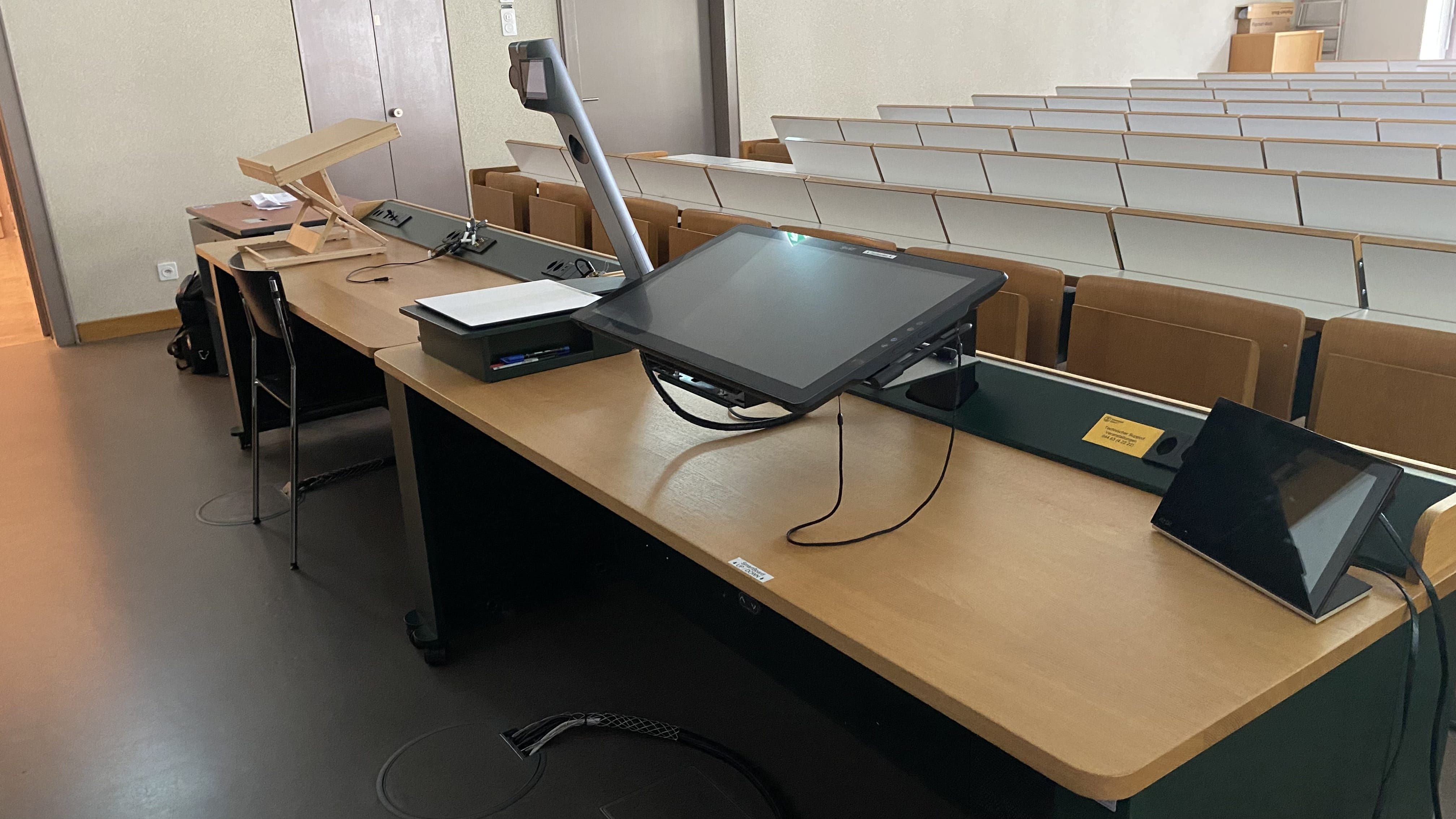 Hörsaal RAK-E-8: Ansicht auf das Dozierendenpult. Links davon befindet sich der Tisch mit Rollstuhl-Signet.