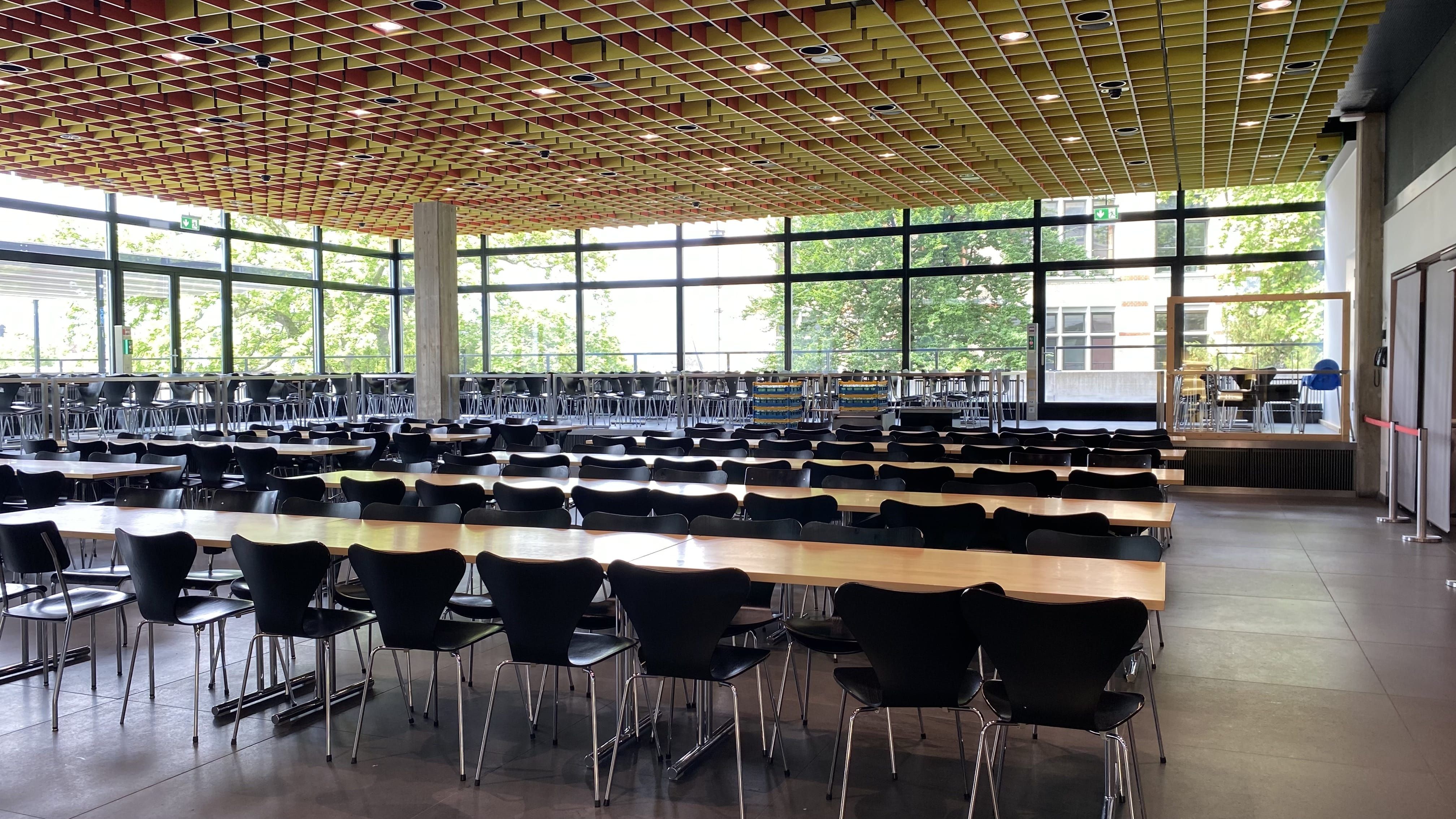 MEN-B, Mensa: Ansicht auf die ebenerdige Bestuhlung in der Mensa. Die Mensa verfügt auch über einen erhöhten Sitzbereich der nur durch Stufen erreicht werden kann.