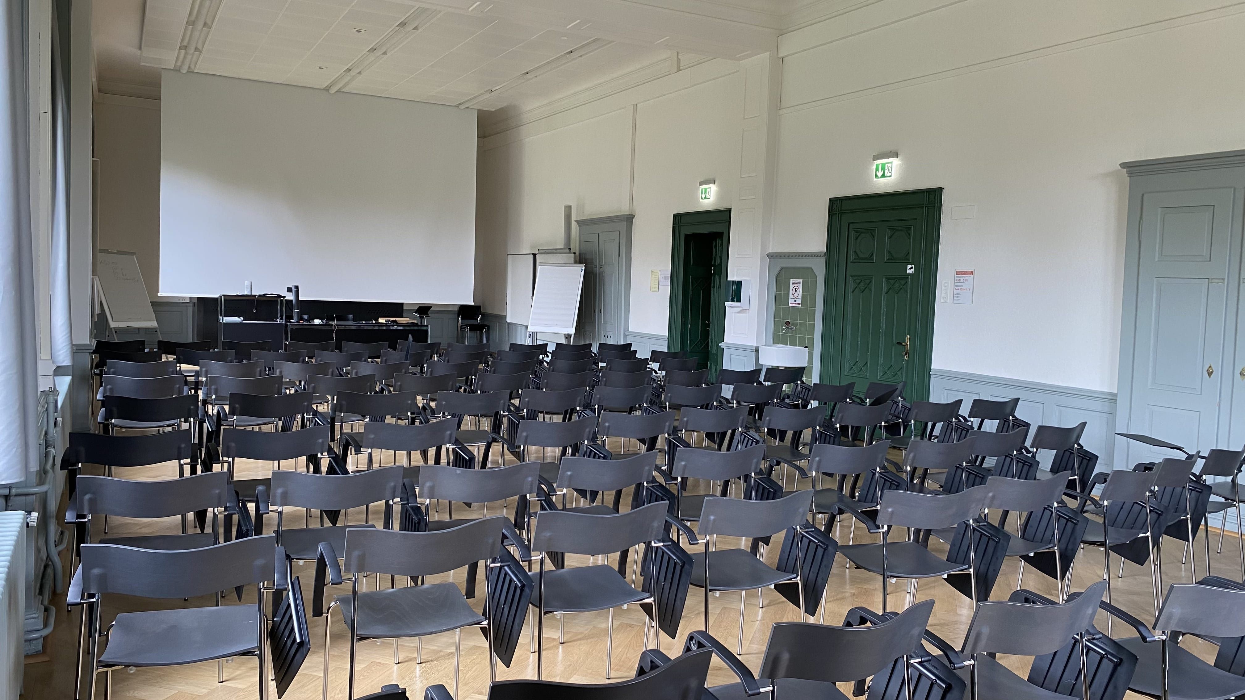 Hörsaal KAB-G-01: Ansicht auf den Raum zum Dozierendenpult hin. Die Eingangstüren befinden sich rechts im Bild.