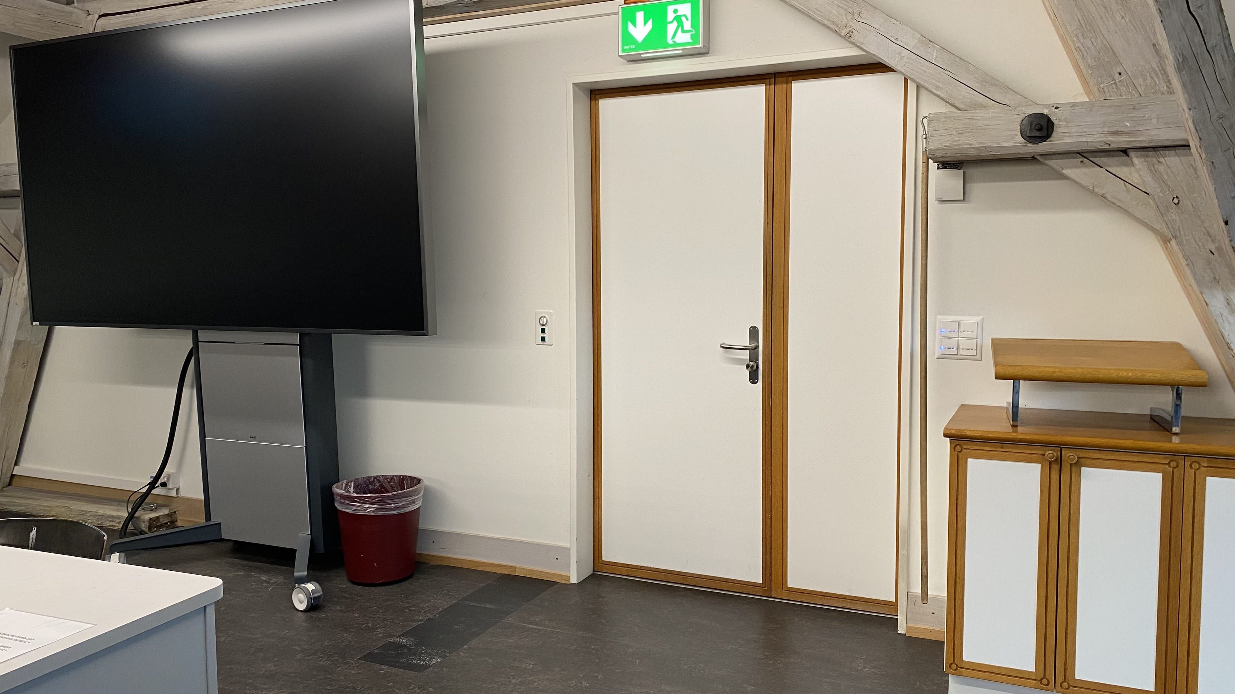 Seminarraum KIR-3-308: Ansicht auf die Eingangstüre des Seminarraumes. Links von der Türe aus befindet sich ein Lavabo.