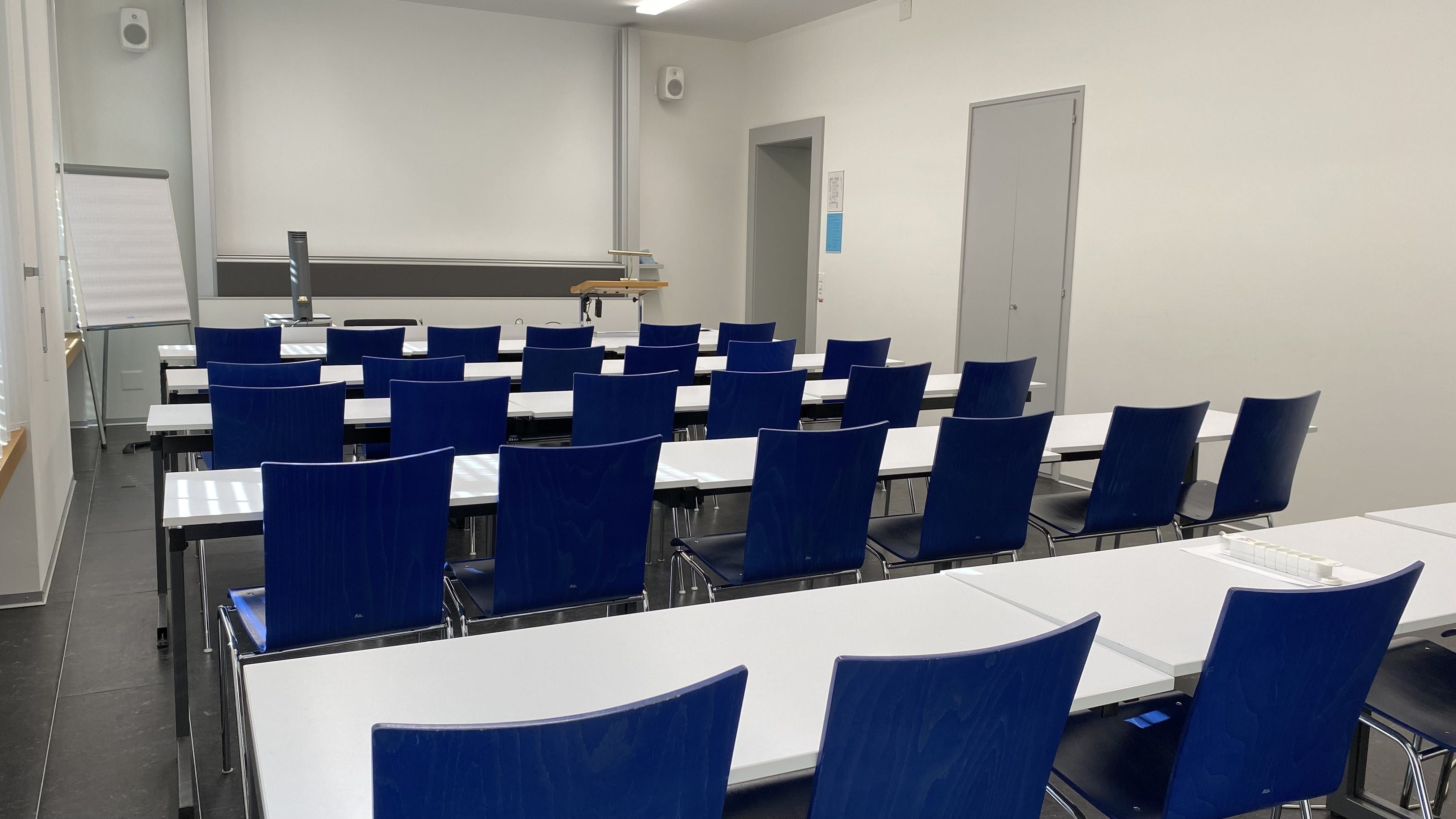 Seminarraum PLD-E-04: Ansicht auf den Raum zum Dozierendenpult hin. Die Eingangstüre befindet sich rechts im Bild.