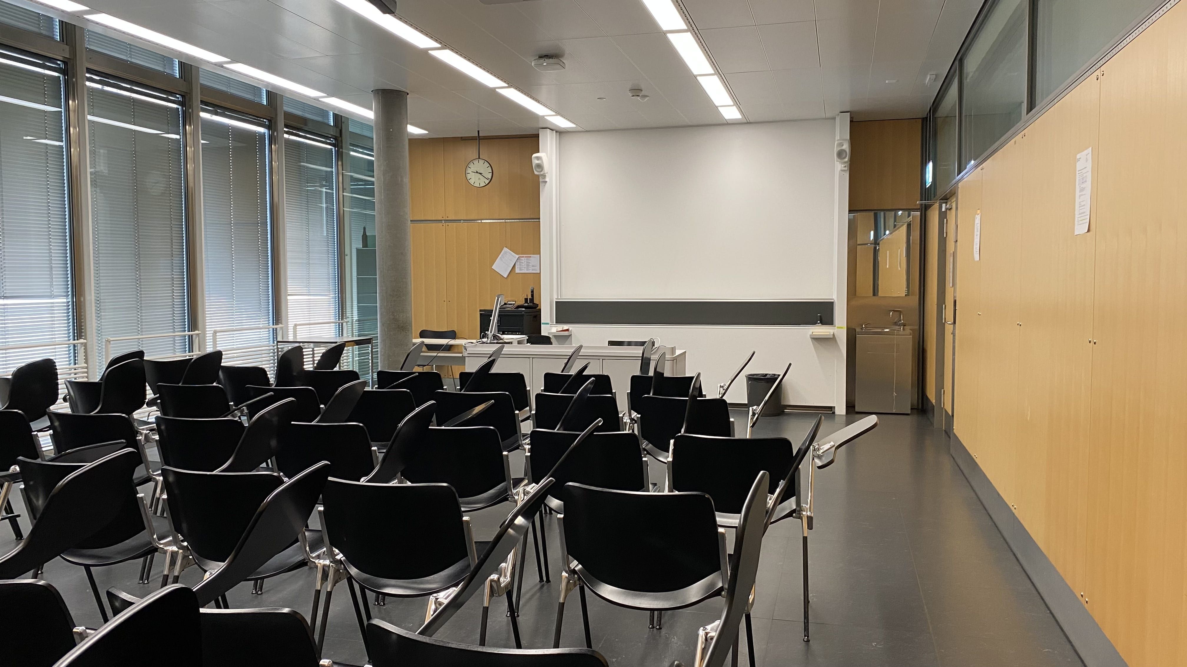 Seminarraum PLF-C-104: Ansicht auf den Raum von der hinteren Eingangstüre aus zum Dozierendenpult hin.
