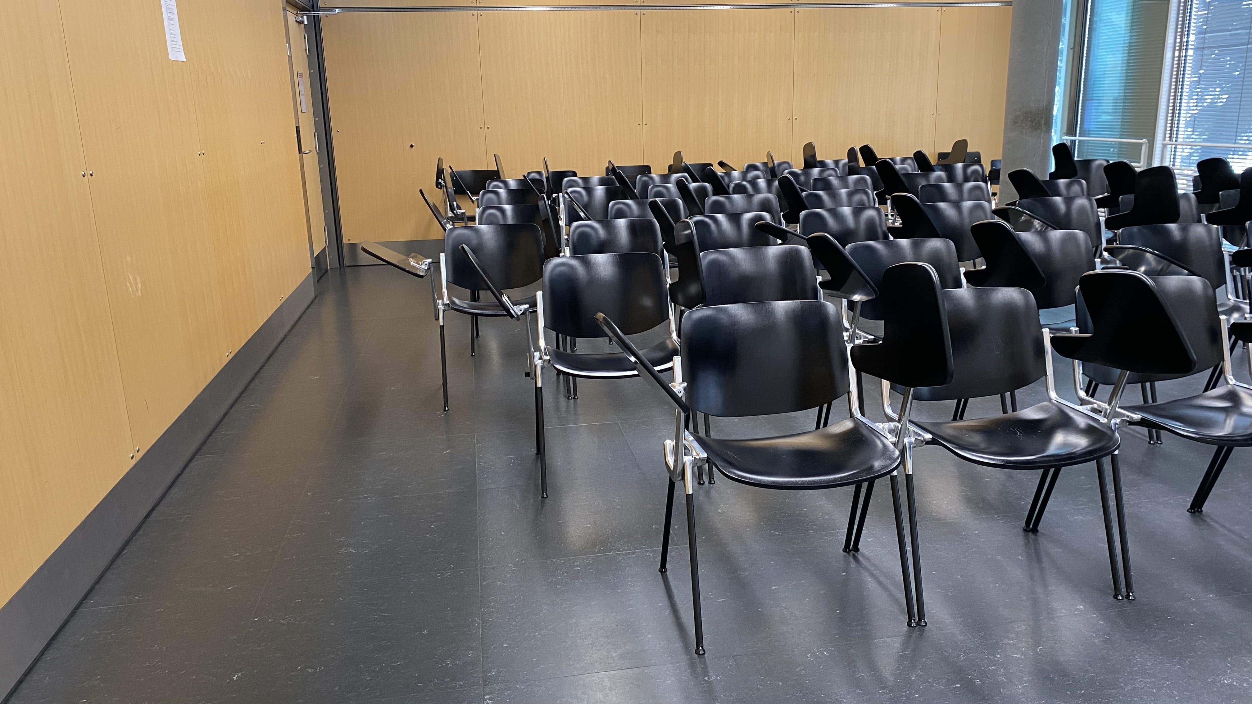 Seminarraum PLF-C-104: Ansicht auf die linke Seite der Stuhlreihen mit breiten Durchgang vom Dozierendenpult aus.