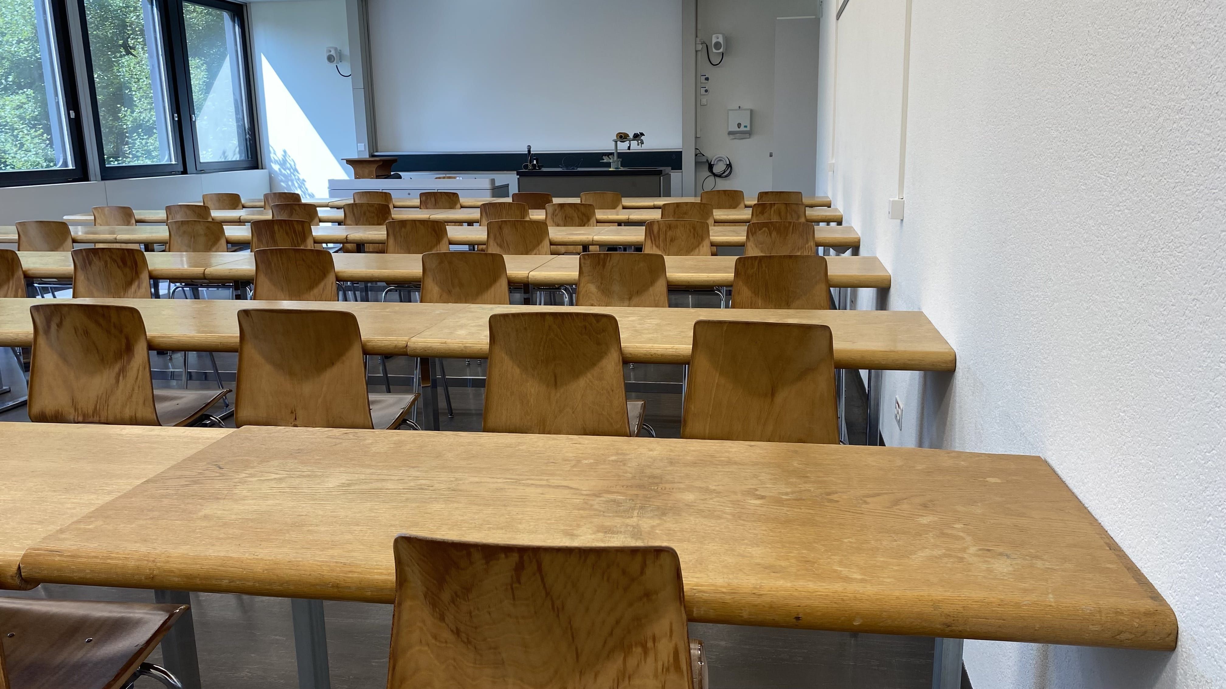 Hörsaal BOT-P1-41: Ansicht auf die rechte Seite der Stuhlreihen. Die Tische schliessen an der Wand an, es gibt keinen Durchgang.