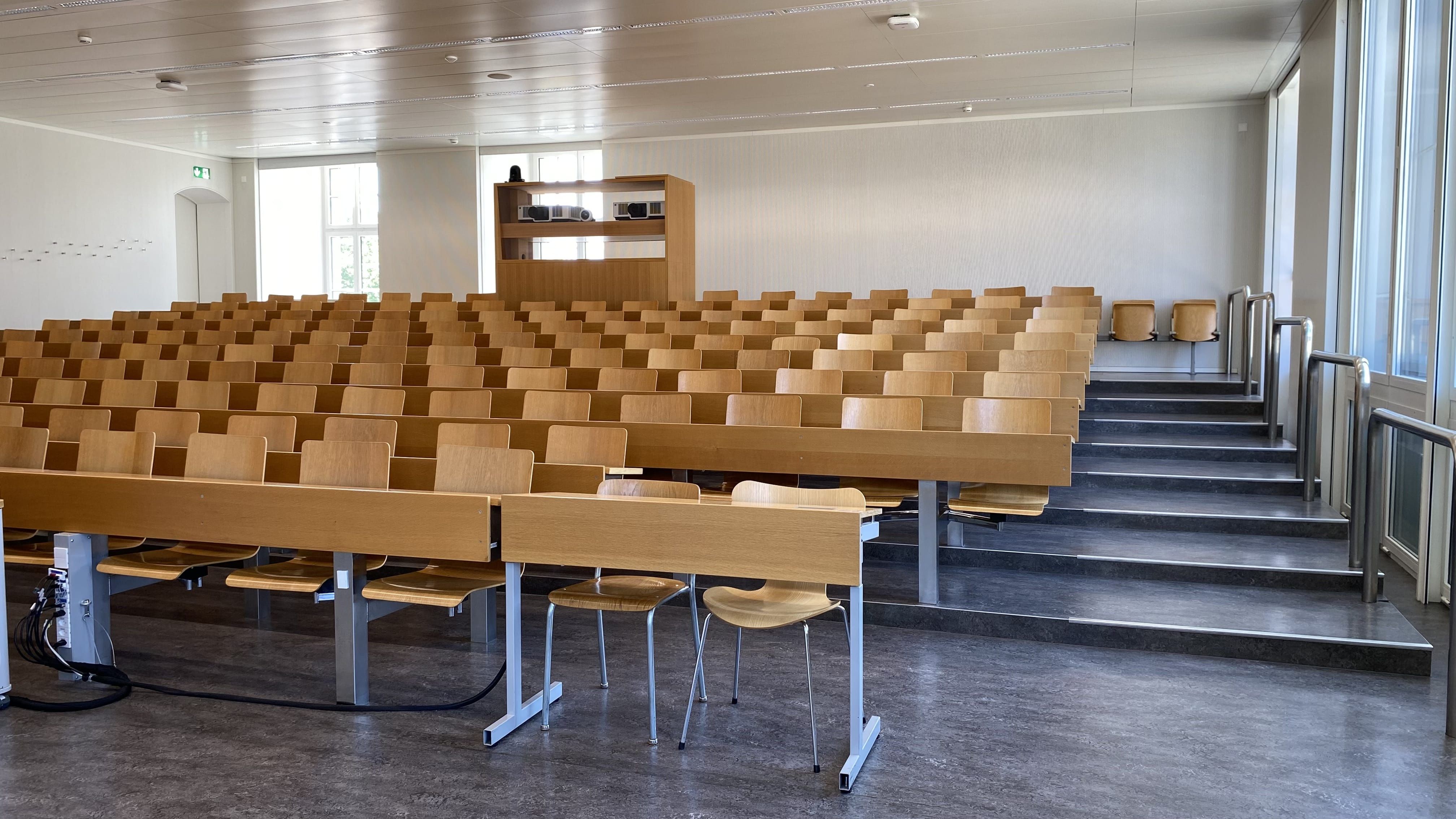 Seminarraum RAI-G-41: Ansicht auf den Raum vom Dozierendenpult aus. Treppenstufen führen links und rechts zur hintersten Reihe.