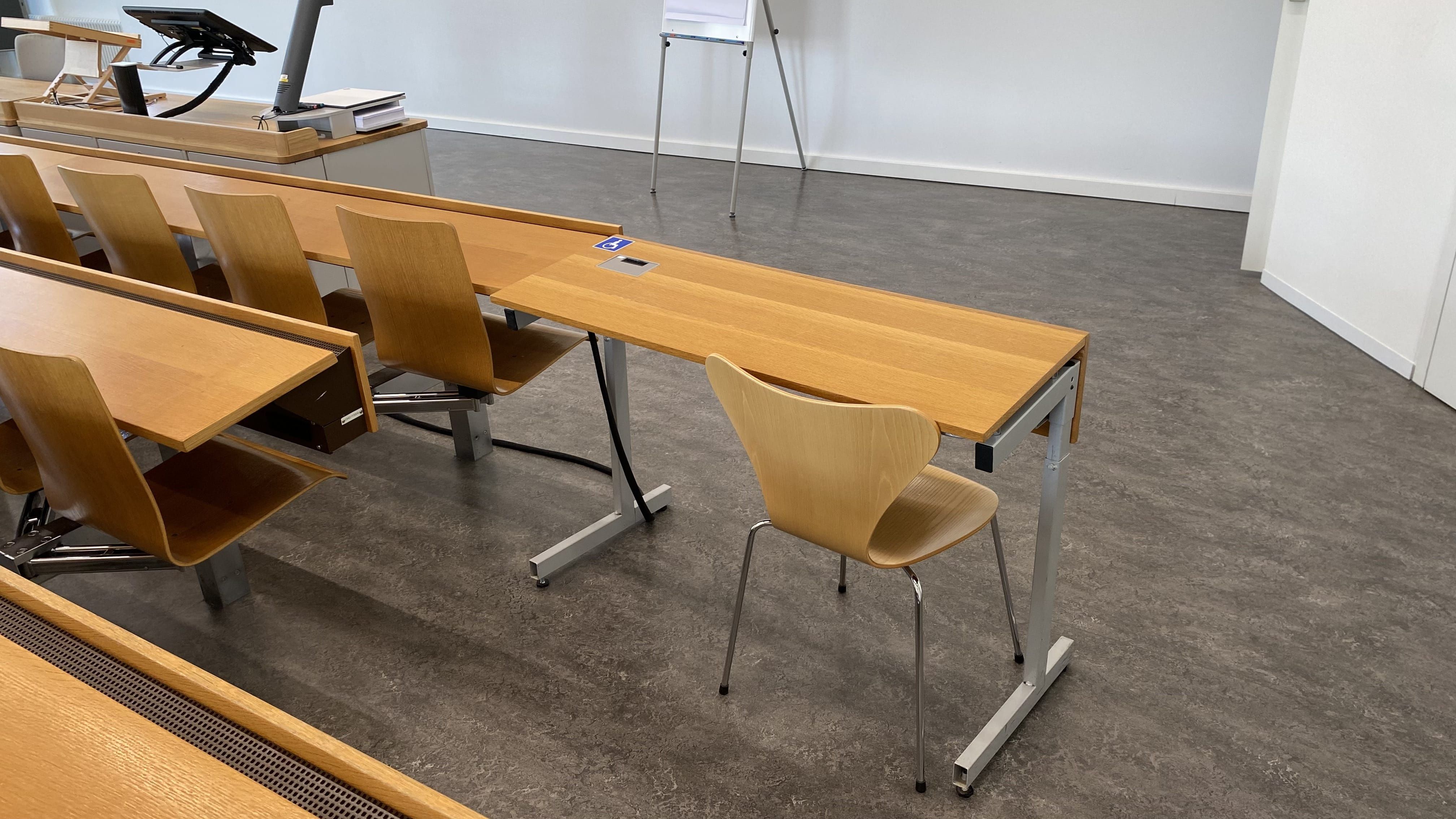 Seminarraum RAI-G-41: Ansicht auf den ersten von zwei Tischen mit Rollstuhl-Signet und ohne fixe Bestuhlung in der vordersten Reihe. Dieser Tisch befindet sich direkt neben der Eingangstüre auf der rechten Seite des Raumes.