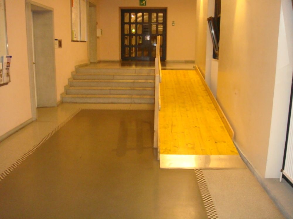 KO2, Stockwerk G: Kleine Holz-Rampe (Steigung 15 %) zum Durchgang zu KOL. Alternativ kann die flachere Beton-Rampe (Steigung 6 %) vom rechten Flur benutzt werden, welche zum selben Durchgang führt.