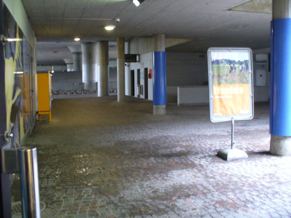 Y50, Stockwerk E: Sicht vom Eingang des ASVZ Sport-Center Irchel aus zu den drei Aufzügen des Parkhauses. Entfernung etwa 30 Meter. Der Weg führt über Pflastersteine.