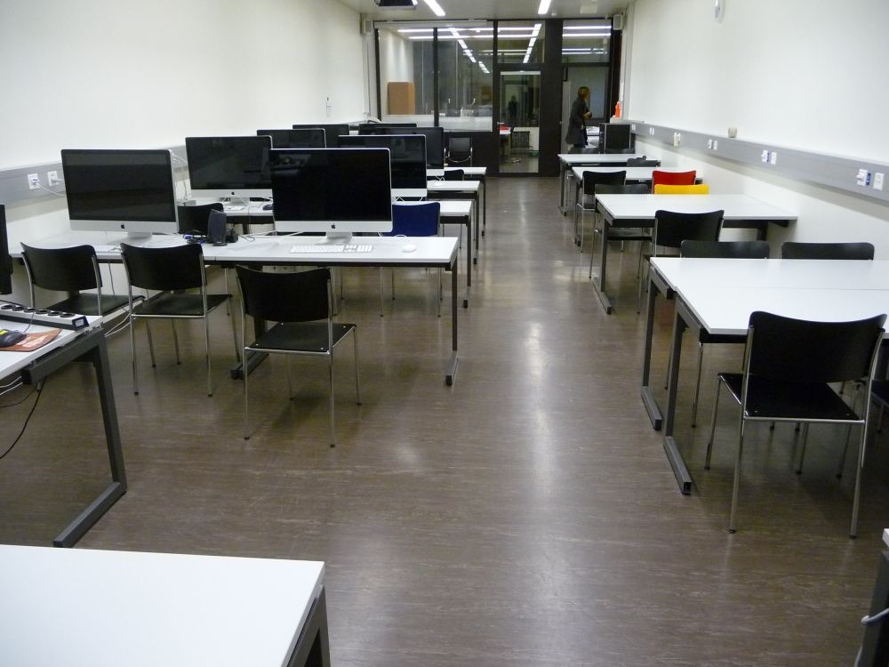 Computerkurs-Raum Y25-G-66a: Computerkurs-Raum von der gegenüberliegenden Seite aus betrachtet. Hinten sieht man durch die Glaswand auf zwei Büroräume. Rechts davor befindet sich die Ausgangs-Tür.