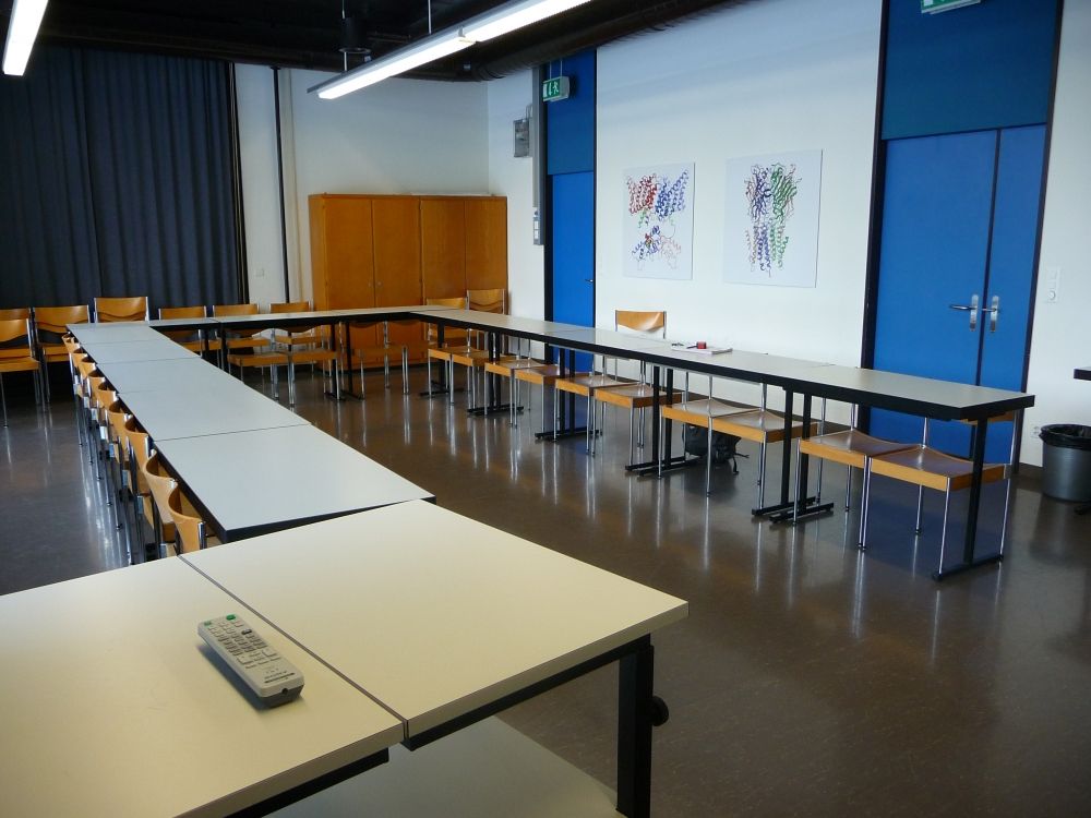 Seminarraum Y44-H-11: Raum aus einer schrägen Perspektive. Die rechte Tür im Bild verfügt über einen Tür-Teil, durch den sich die Tür verbreitern lässt, die linke nicht.