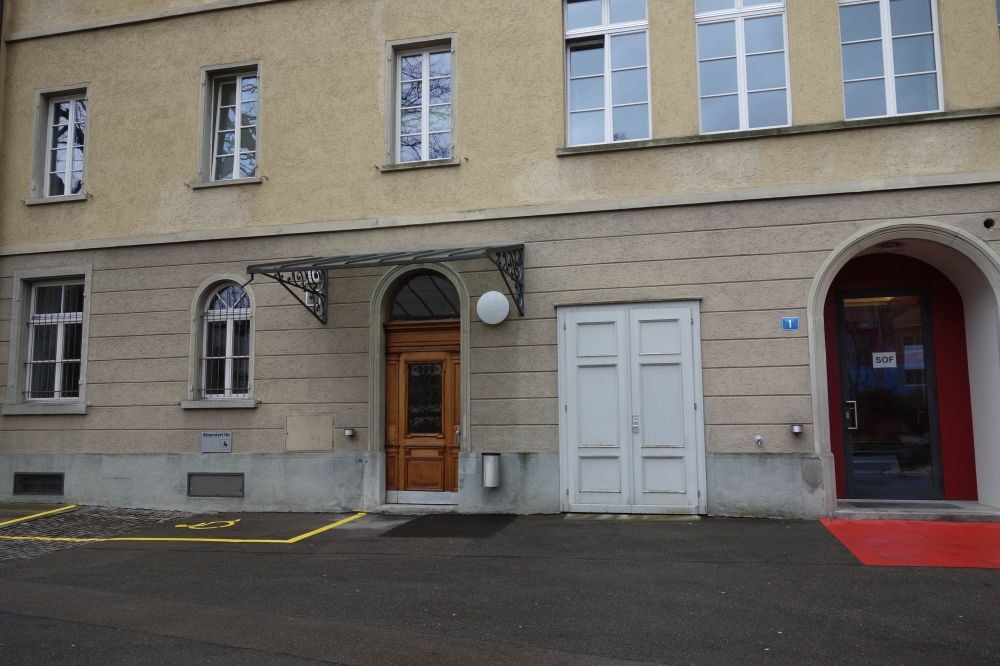 Gebäude SOF: Links ein Rollstuhlparkplatz, rechts der Haupteingang.