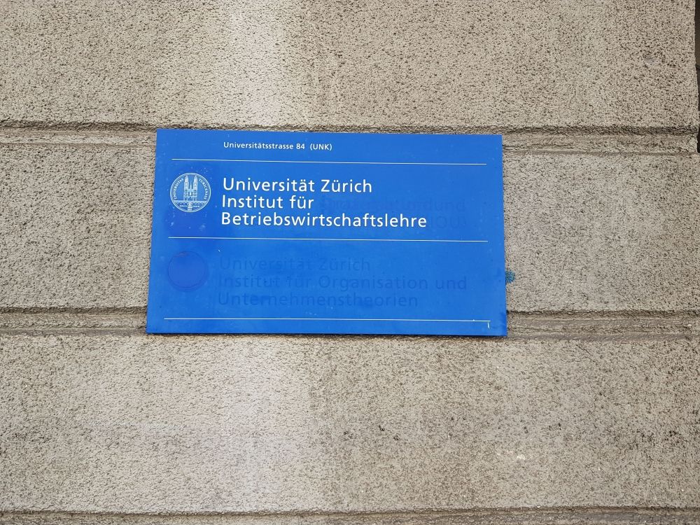 Gebäude UNK: Schild ausserhalb des Gebäudes, links neben dem Eingang.