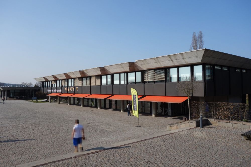 Gebäude Y10: Gesamtansicht des Gebäudes. Vorne rechts befindet sich der Haupteingang bei der gelben Fahne. Im Hintergrund ist das Gebäude Y00 zu sehen.