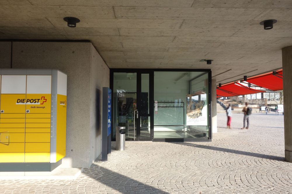 Gebäude Y10: Der alternative Eingang auf der linken Seite des Gebäudes, der zum anthropologischen Museum führt. Vorne links sind ist die MyPost24-Station zu sehen.