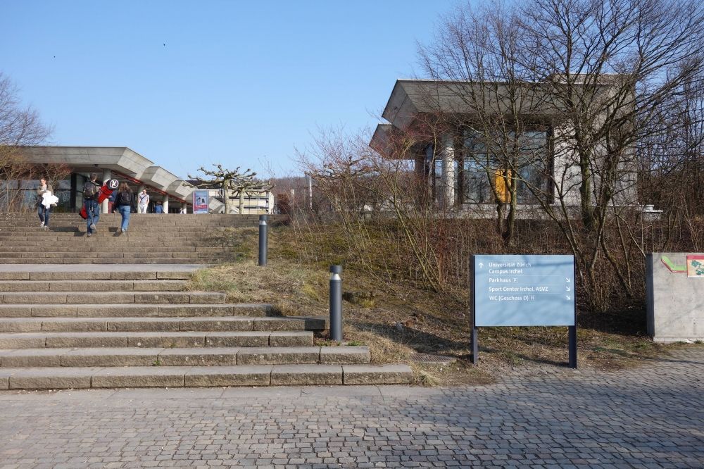 Gebäude Y30: Der Zugang zum Gebäude vom Irchelkomplex her erfolgt über eine Treppe rechts des blauen Schildes oder über den Lift des Gebäude Y50, der oben rechts im Bild zu erkennen ist.