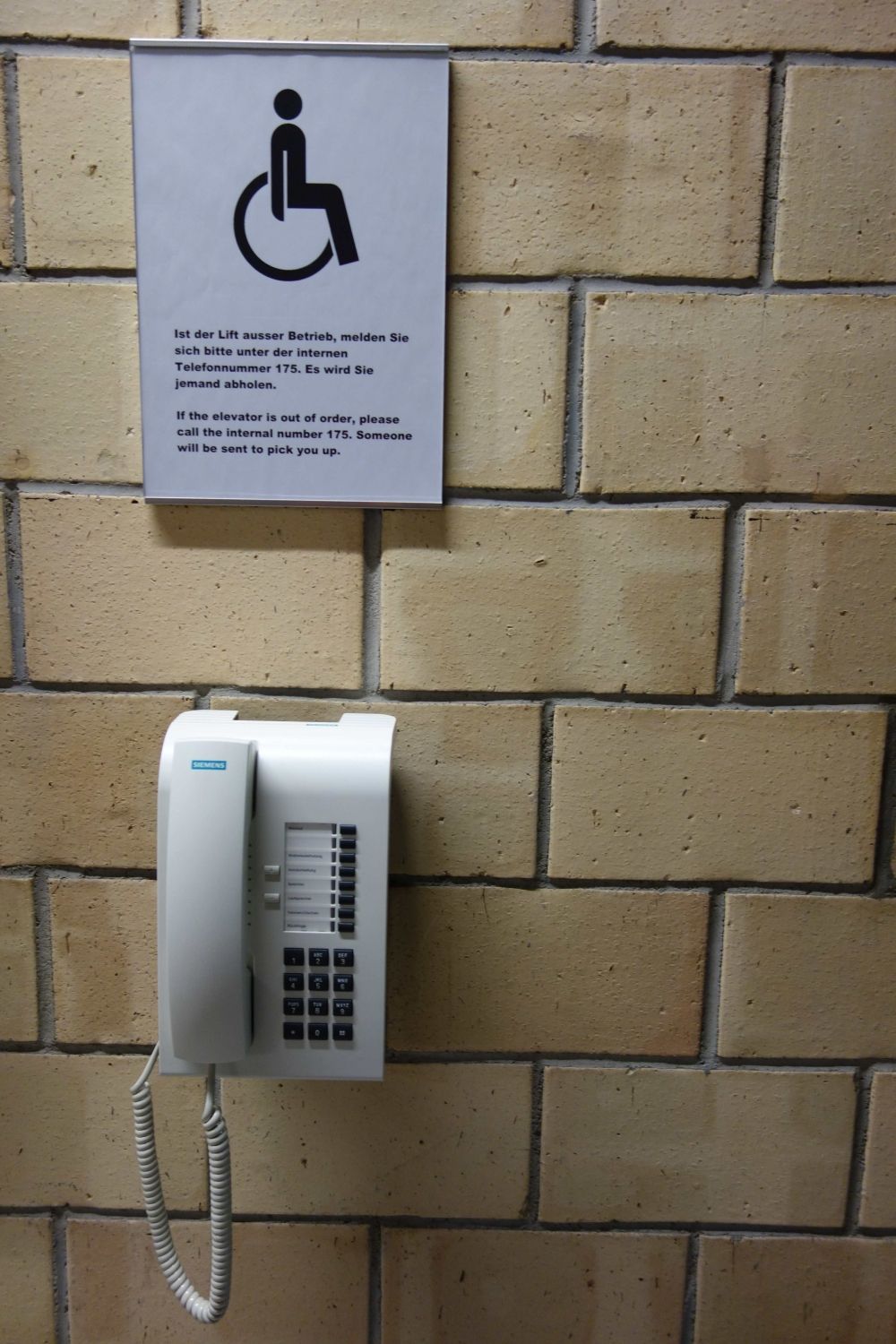 Y21, Stockwerk D: Unmittelbar nach dem Eingang, Telefon mit Anweisungen für Rollstuhlfahrende, falls der Lift nicht funktioniert.