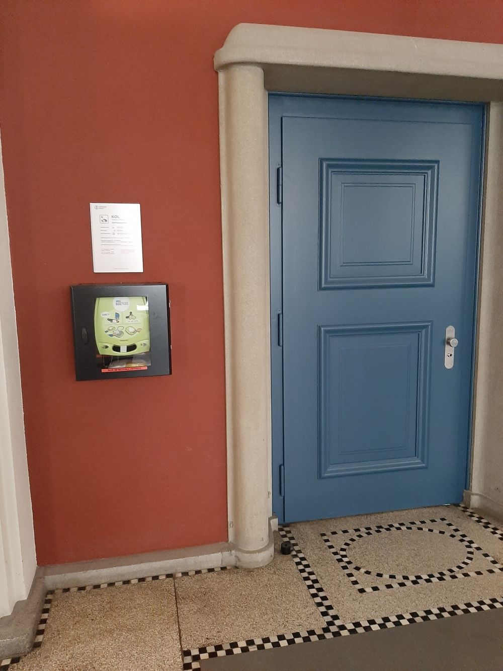 Büro KOL-E-1a: Defibrillator links neben dem Eingang zum Büro