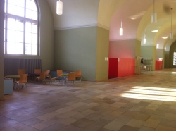 KOL-D, Halle: Sitzgelegenheiten und Weg (jeweils bei den roten Wänden) über Stufen hinunter zum Hörsaal KOH-B-10.