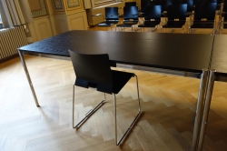 Aula RAA-G-01: Tisch beim Rednerpult. Im Hintergrund sind die Stühle mit Klapptischchen zu sehen.