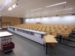 Hörsaal Y16-G-05: Sicht auf den gesamten Raum.
Rechts und links sind die Tische ohne fix montierte Stühle.