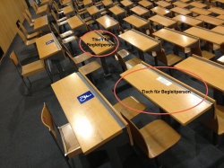 Hörsaal Y24-G-45: Beide mit Rollstuhl-Signet markierte Tische und eine Reihe weiter vorne die beiden Tische für die Begleitperson (rote Kreise und Beschriftung).